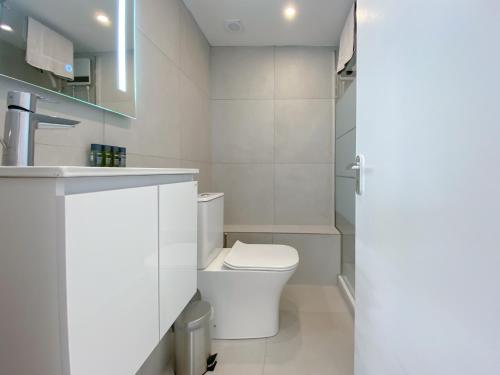 La salle de bains blanche est pourvue de toilettes et d'un lavabo. dans l'établissement Phaedrus Living: Nicosia Downtown Flat 704, à Nicosie