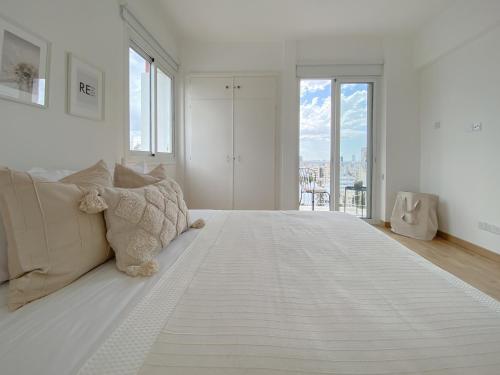 - une chambre blanche avec un grand lit blanc et des fenêtres dans l'établissement Phaedrus Living: Nicosia Downtown Flat 704, à Nicosie