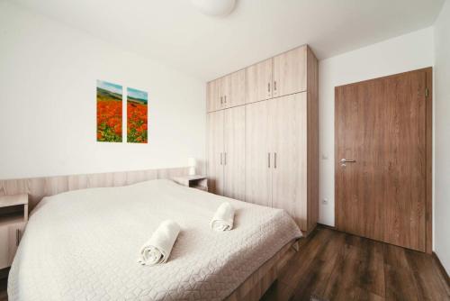 a bedroom with a white bed and a wooden cabinet at D&B Lelle Apartman in Balatonlelle