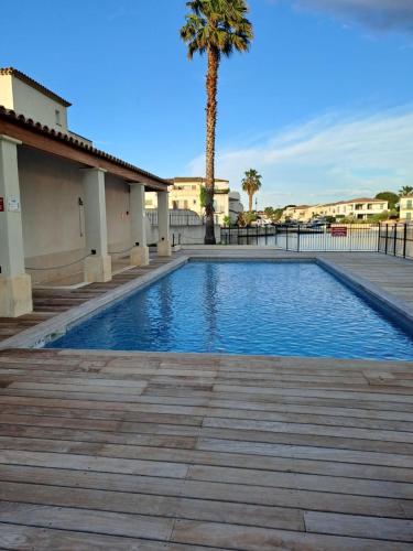 - une piscine avec un palmier à côté d'un bâtiment dans l'établissement Belle marina avec ponton et piscine collective, à Aigues-Mortes