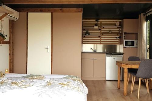 Cet appartement comprend une chambre avec un lit et une table ainsi qu'une cuisine. dans l'établissement Tiny House à la campagne, à Saint-Yan