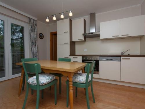 een keuken met een houten tafel en groene stoelen bij Apartment Kornblume by Interhome in Velden am Wörthersee