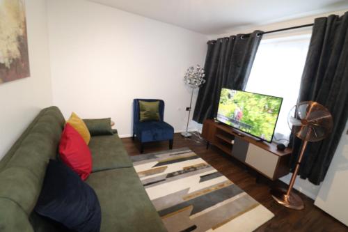 a living room with a green couch and a flat screen tv at Central Modern House, Greenhithe in Kent