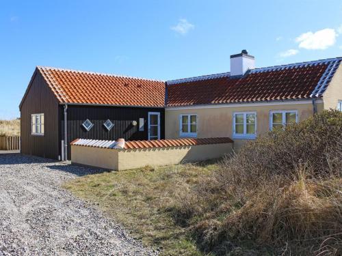 a small house with a brown roof on a gravel road at Holiday Home Nille - 100m from the sea by Interhome in Skagen