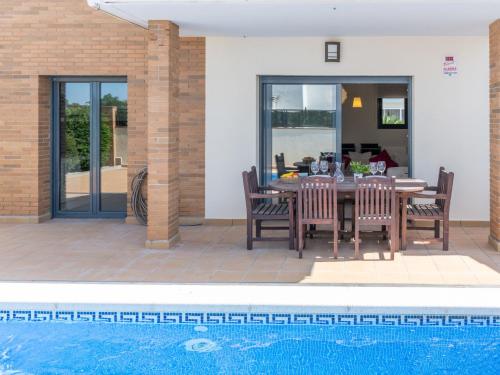 un patio con mesa y sillas junto a una piscina en Holiday Home Mestral by Interhome, en Empuriabrava