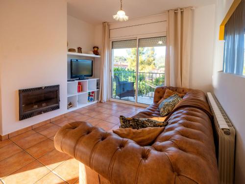 a living room with a brown leather couch and a television at Holiday Home Origin by Interhome in Olivella