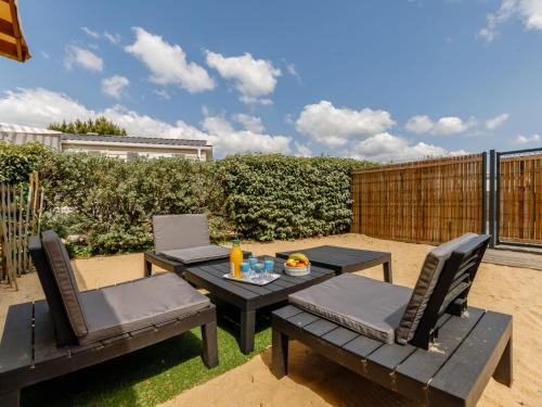un patio con 2 mesas y sillas en el césped en Holiday Home New Cottage de 2020 by Interhome, en Saint-Hilaire-de-Riez