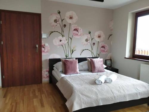 ザコパネにあるApartament na Antałówceのベッドルーム1室(ピンクの花が飾られた壁のベッド1台付)
