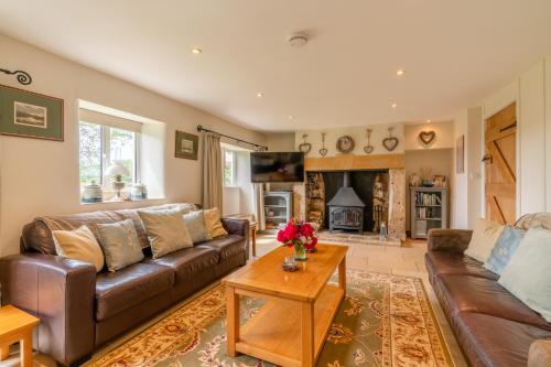 a living room with a brown leather couch and a fireplace at Bill's Cottage in Northleach