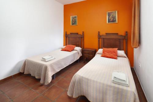 two beds in a room with orange walls at Casa Rural Los Hidalgos in Tolatán