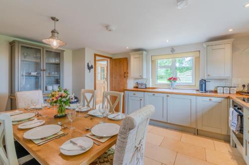 een keuken met een houten tafel met stoelen en een eetkamer bij Bill's Cottage in Northleach
