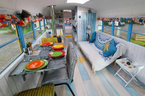 a table and chairs on a rv with a table and a couch at American School Bus Glamping - Somerset in Cheddar