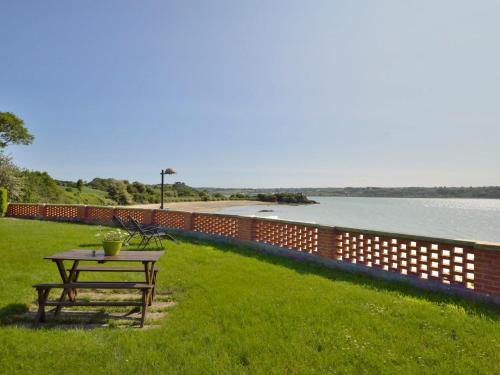 a picnic table in the grass next to a body of water at Holiday Home Ker Yannick by Interhome in Hillion