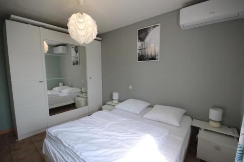 une chambre avec un lit blanc et un miroir dans l'établissement Agréable Maison de vacances climatisee, 2 chambres pour 5 couchages, Résidence securisee avec piscine commune LE CLOS DE SOCORRO, 800m de la plage Portiragnes plage LRCS95, à Portiragnes