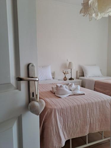 a white bedroom with two beds with towels on the bed at Maison Du Lac in Kanoni