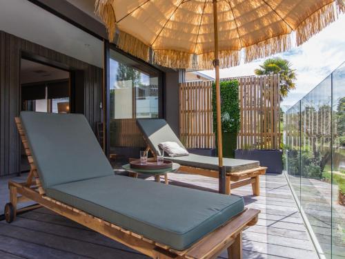 une terrasse avec une chaise et un parasol dans l'établissement Holiday Home Lartigau by Interhome, à Capbreton