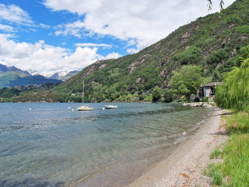 a beach with boats in the water next to a mountain at Apartment Vento Errante by Interhome in Dorio