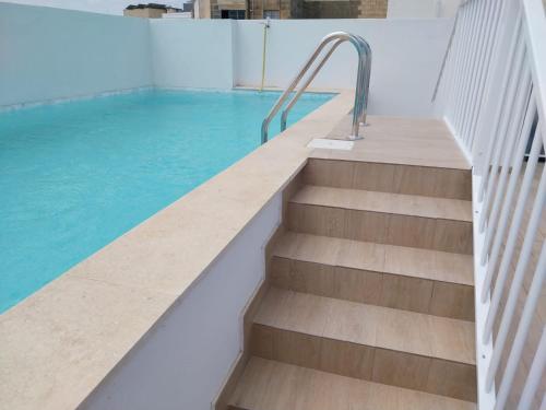a swimming pool with stairs and blue water at St gaetans studio apartment 6A in Tas-Samra