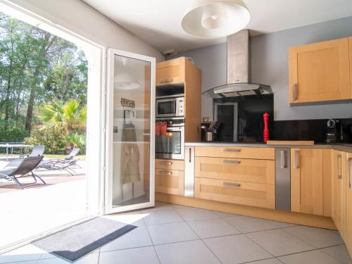 une cuisine avec une porte coulissante en verre menant à une terrasse. dans l'établissement Holiday Home Villa Matisse by Interhome, à Bagnols-en-Forêt