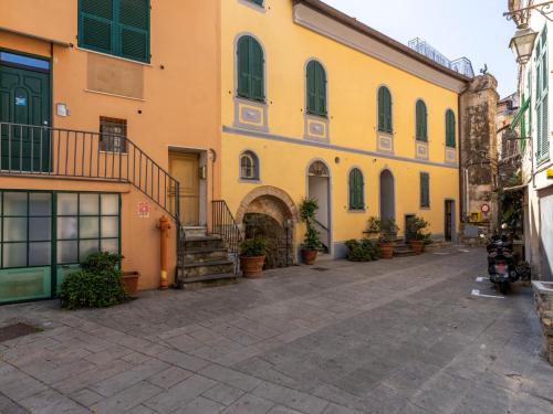 a yellow building with potted plants on a street at Apartment Ruscus by Interhome in Terzorio