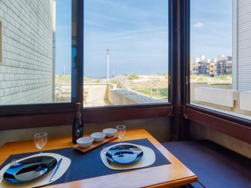a table with two plates and wine glasses and a window at Apartment Les Terrasses de l'Atlantique-7 by Interhome in Lacanau-Océan