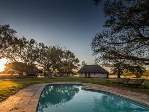 une piscine dans une cour avec un bâtiment en arrière-plan dans l'établissement La Rochelle Lodge Namibia Tsumeb, à Tsumeb