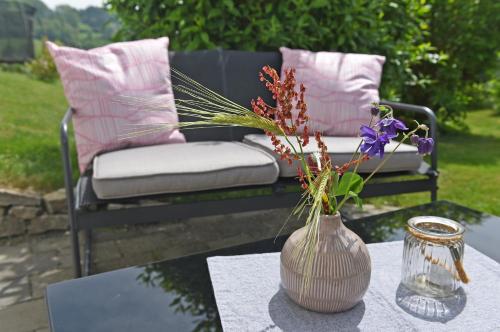 a vase with flowers on a table with a chair at Ferienwohnung Familie Strehl in Frickingen