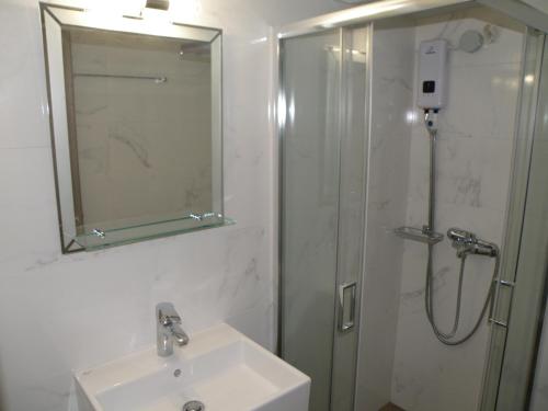 a bathroom with a sink and a shower with a mirror at Talos apartments and studios in Heraklio Town