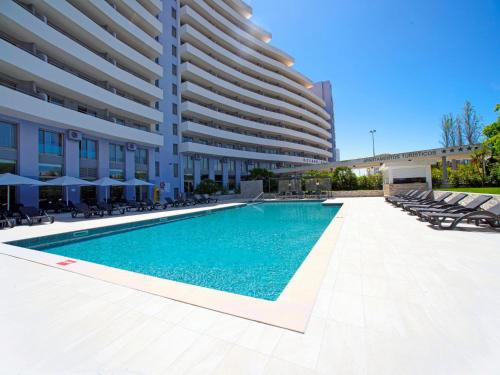 a swimming pool in front of a large building at Apartment Full moon by Interhome in Portimão