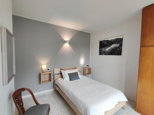 a bedroom with a white bed with two lights on the wall at Apartment Stazione by Interhome in Porlezza
