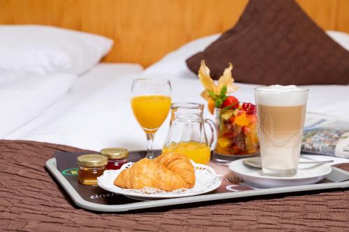 a tray with breakfast foods and drinks on a bed at Parkhotel Rügen in Bergen auf Rügen