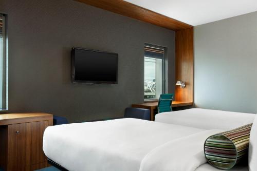 a hotel room with two beds and a flat screen tv at Aloft London Excel in London