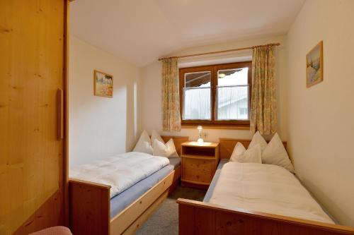 two beds in a small room with a window at Landhaus Kröll - Barbara Kröll in Ellmau