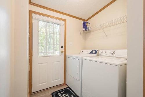 a laundry room with a washer and a white door at *Entire House • Sleeps 9 • Hot tub • Pets Welcome* in McHenry