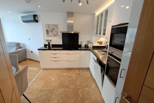 a kitchen with white cabinets and a stove top oven at Seaside Serenity Oasis - High floor - Stunning Views in Gibraltar
