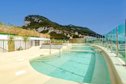 a swimming pool with a mountain in the background at Seaside Serenity Oasis - High floor - Stunning Views - 1BR in Gibraltar