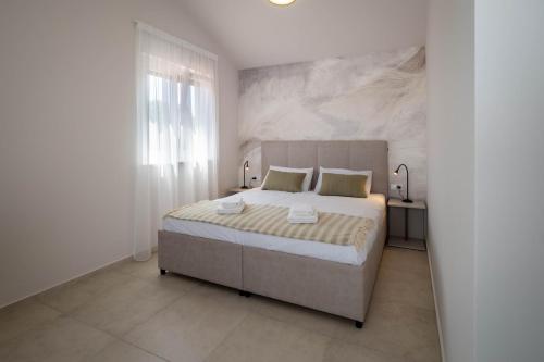 sypialnia z dużym łóżkiem i dużym oknem w obiekcie Villa Monika w Krku