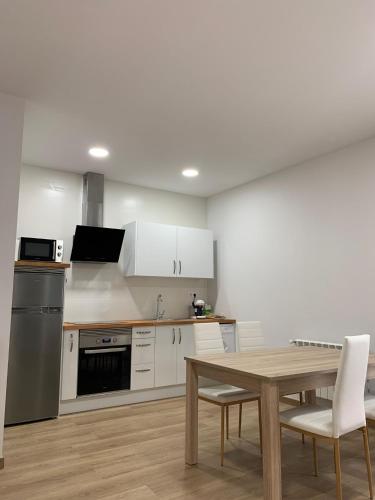 a kitchen with white cabinets and a wooden table at Castiñeiras Street 2 in Sarria