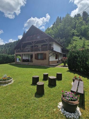 a house with stools in the grass in front of it at Casa Bella in Vadu Moţilor