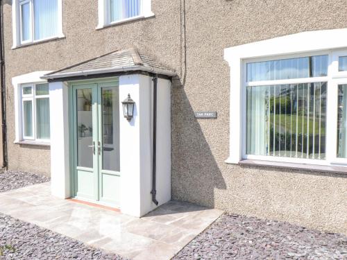an entrance to a house with a green and white door at Tan Parc in Pwllheli