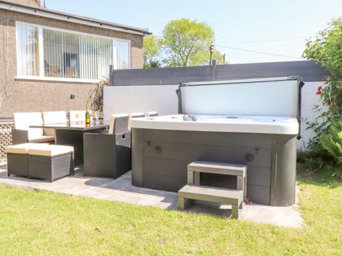 a backyard with a tub and a table and benches at Tan Parc in Pwllheli