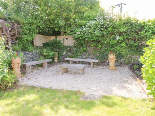 two picnic benches in a garden with a stone wall at Tan Parc in Pwllheli