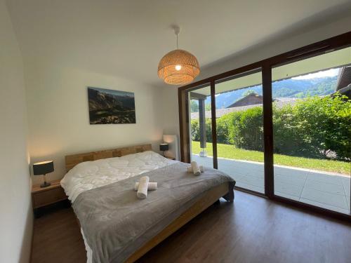 une chambre avec un grand lit et une grande fenêtre dans l'établissement Appartement familial avec terrasse et vue montagne près du centre - FR-1-624-133, à Samoëns
