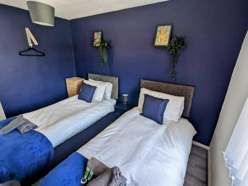 西部德比的住宿－No 51 - Spacious 3 Bed Home - Free Parking - Wi-Fi - Contractors，蓝色墙壁客房的两张床