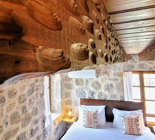 een bed in een kamer met een stenen muur bij Authentic Bodrum Villa with Special Private Pool in Ortakent