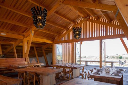 comedor con mesas de madera y ventanas grandes en QUINTA DA FAÍSCA - Agro Turismo, en Favaios