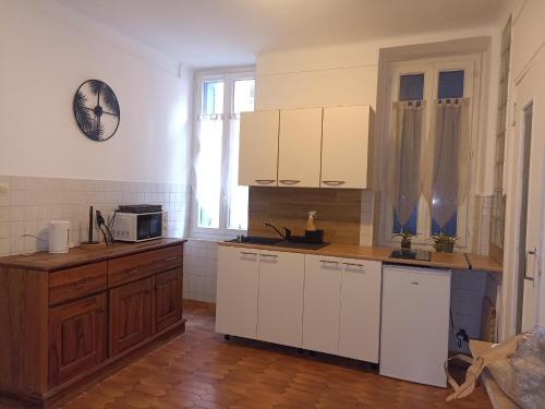 een keuken met witte kasten en een klok aan de muur bij hébergement de la plage en ville in Martigues