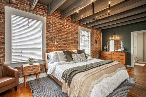 a bedroom with a large bed and a brick wall at The Loft at 113 - Gateway to the North Texas Hill Country in Muenster