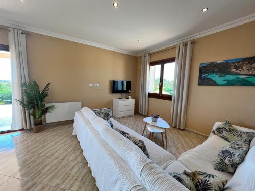 Villa Octopus by Bebreeze في مورو: غرفة معيشة مع كنبتين بيضاء وتلفزيون