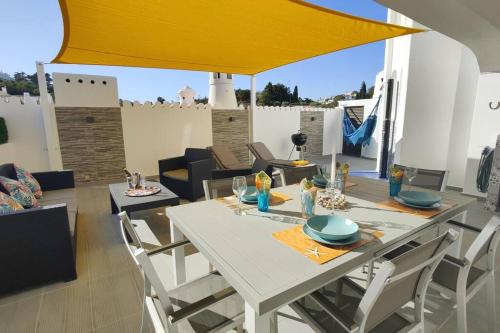 tavolo da pranzo bianco con sedie e ombrellone giallo di ROOFTOP EstrelaDoMar NewOpening- 150m to the Beach a Carvoeiro